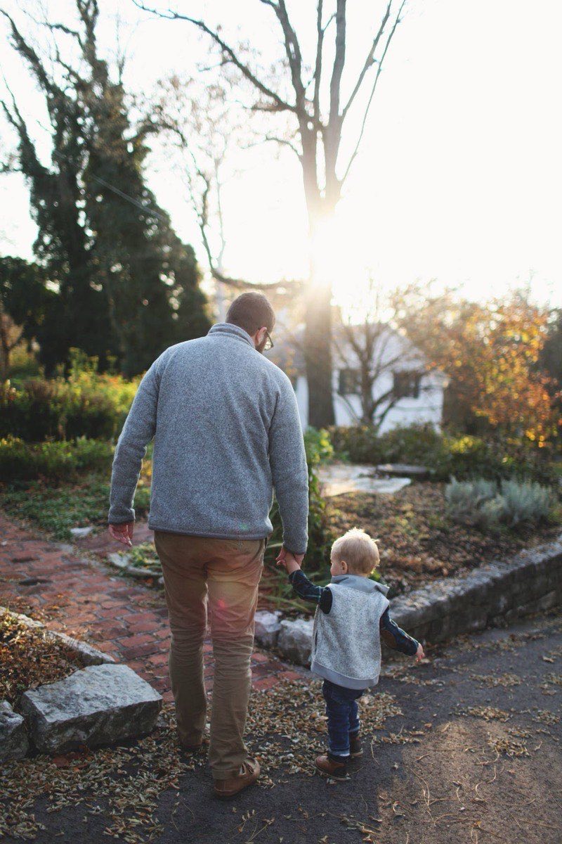 Padre tiene per mano il figlio piccolo in giardino al tramonto